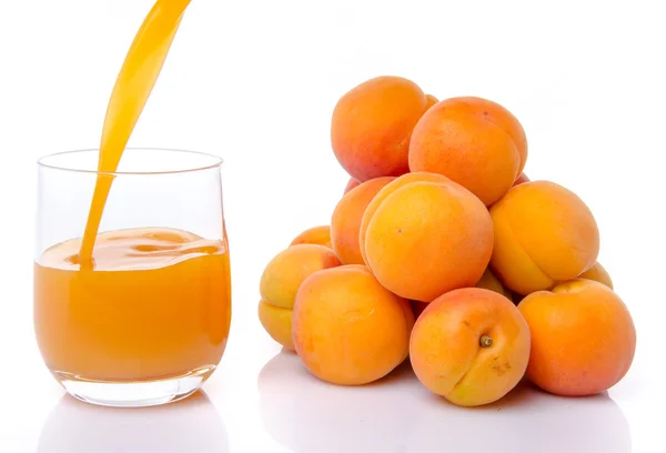 Jus d'abricot versé dans un verre près d'un tas d'abricots — Photo