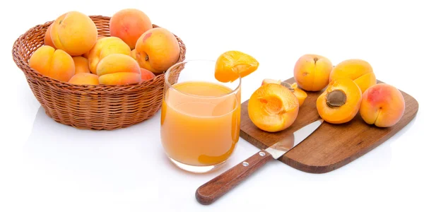 Verre de jus d'abricot avec un panier d'abricots et d'abricots tranchés — Photo