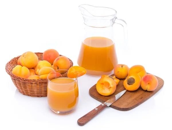 Verre et cruche de jus d'abricot avec un panier d'abricots et sli — Photo