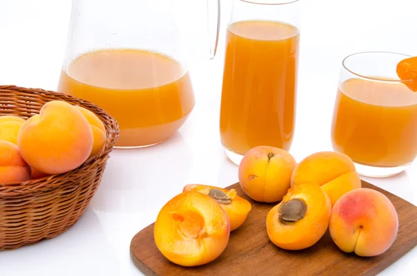 Gobelet et verres de jus d'abricot avec abricots mûrs entiers et tranchés — Photo