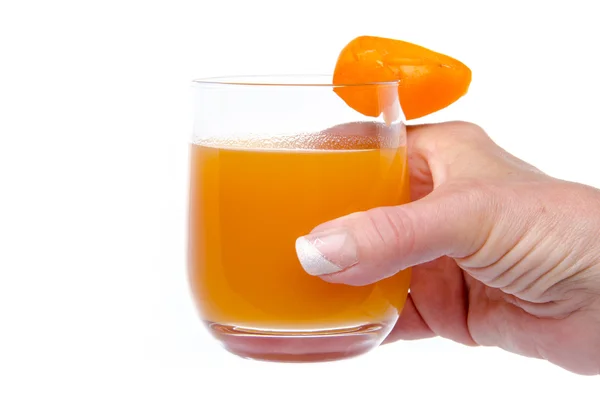 Woman's hand holding a glass of apricot juice — Stock Photo, Image