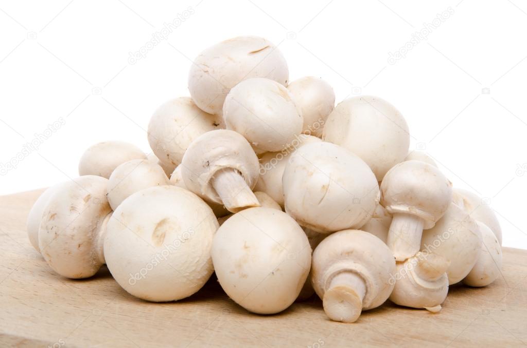 Heap of fresh button mushrooms on a wooden board