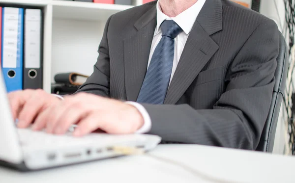 Empresario escribiendo en un teclado de computadora portátil blanco — Foto de Stock