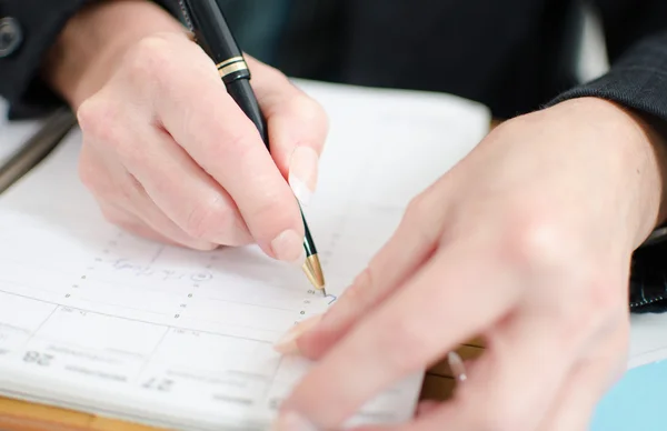 Businesswoman noting an appointment in her diary — Stock Photo, Image