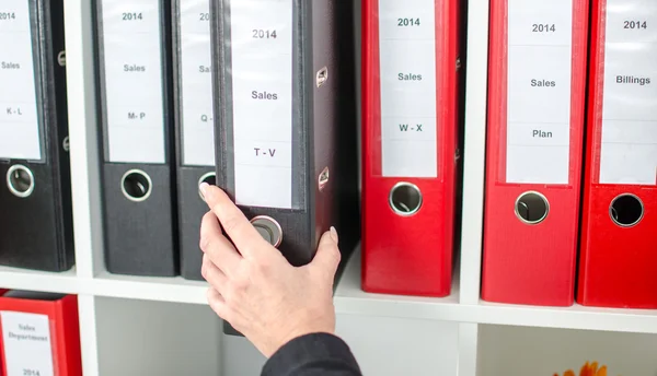 Mano sacando una carpeta de un estante — Foto de Stock