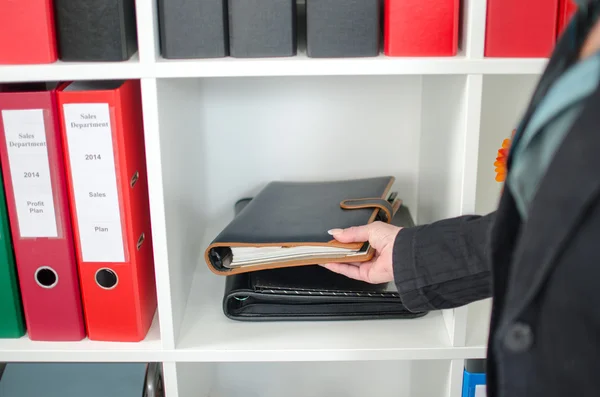 Femme d'affaires prenant un journal d'une étagère — Photo