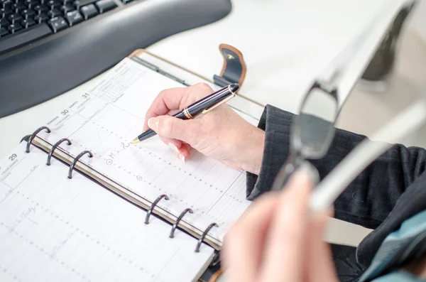 Businesswoman noting an appointment in her diary — Stock Photo, Image