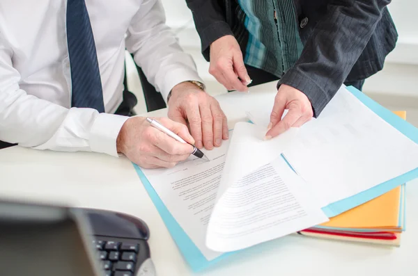 Businessman signing a documents presented by his secretary — Stock Photo, Image