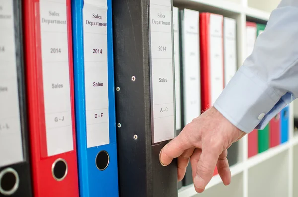 Empresario sacando un aglutinante del estante — Foto de Stock