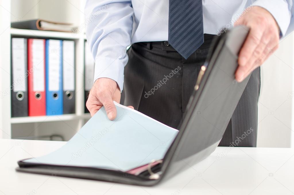 Businessman taking folder from his briefcase