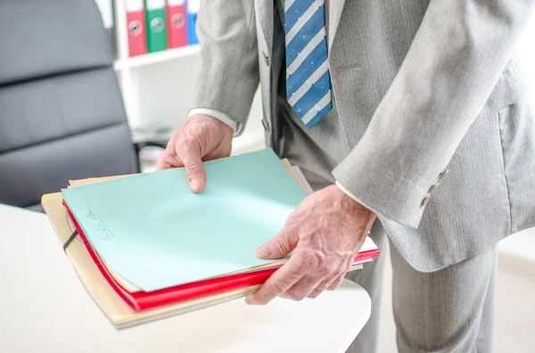 Empresario poniendo archivos en su escritorio — Foto de Stock