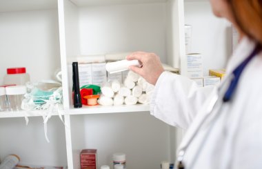 Kadın doktor bir bandaj bir raf alarak