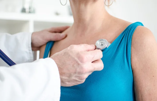 Médico examinando um paciente com um estetoscópio — Fotografia de Stock