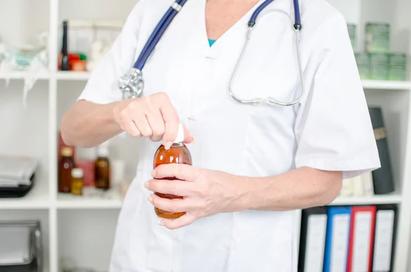 Female doctor opening a syrup bottle — Stock Photo, Image