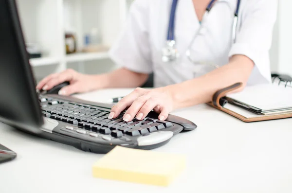 Female doctor taping on a computer keyboard — Stock Photo, Image