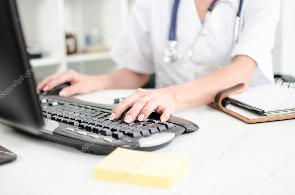 Female doctor taping on a computer keyboard