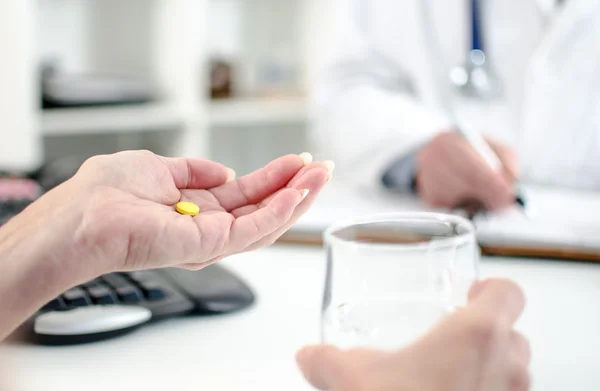 Patienten håller p-piller och glas vatten — Stockfoto