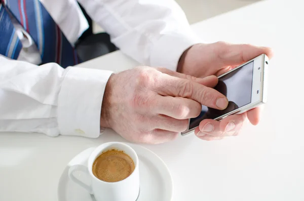 Zakenman texting met smartphone en drinken een kopje koffie — Stockfoto