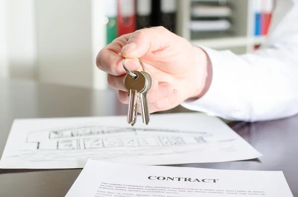 Estate agent holding house keys — Stock Photo, Image