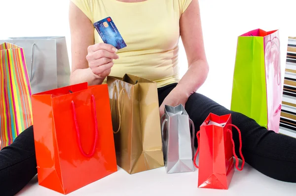 Bir kredi kartı tutan bir kadın çevresinde alışveriş torbaları — Stok fotoğraf