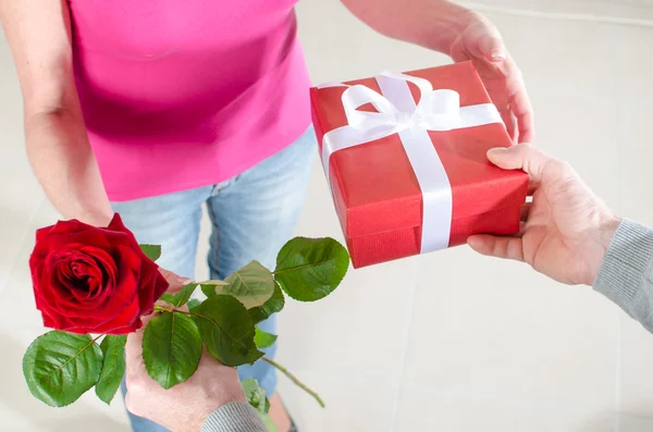 Mann schenkt einer Frau eine Rose und ein Geschenk — Stockfoto