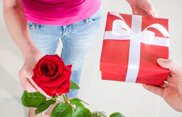 一朵玫瑰和一份礼物给一个女人的男人 — 图库照片