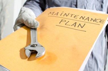 Worker holding a folder of maintenance plan and monkey wrench clipart