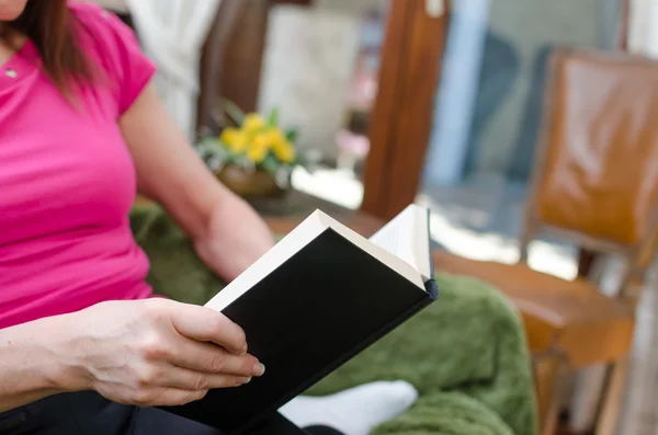 Femme lisant un livre sur un canapé — Photo