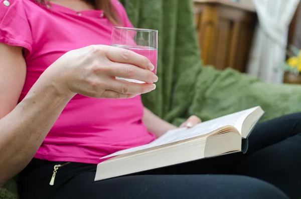 Kadın bir kanepede kitap okuma — Stok fotoğraf
