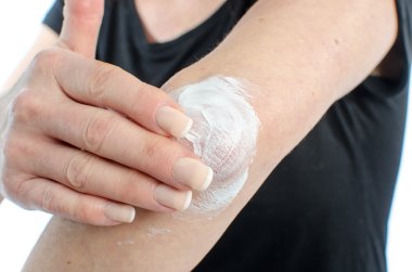 Woman putting cream on her elbow