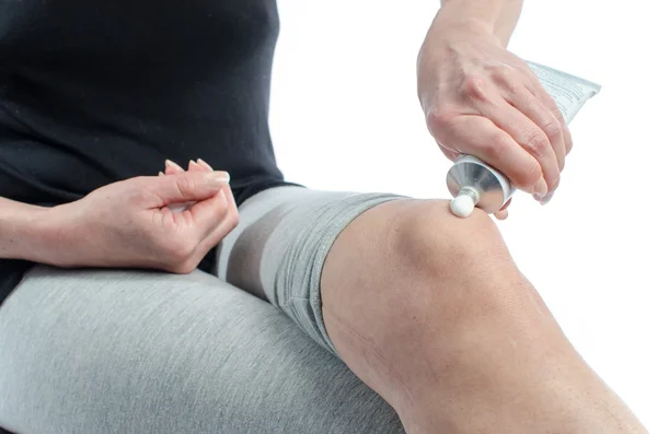 Woman putting cream on her knee — Stock Photo, Image