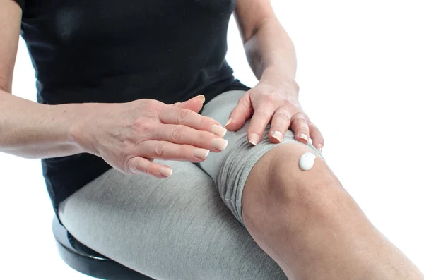 Mujer poniendo crema en su rodilla — Foto de Stock