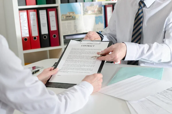 Makler zeigt seinem Klienten einen Nachlassvertrag und die Schlüssel — Stockfoto