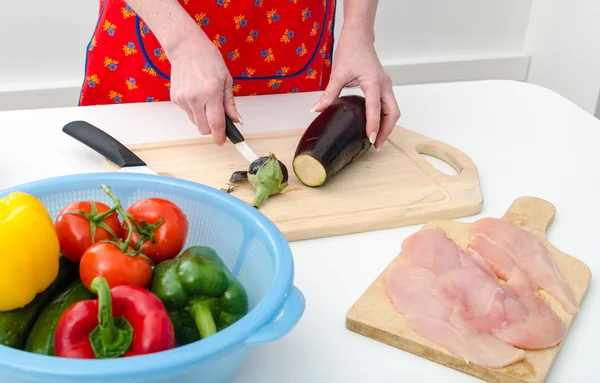 Händerna på kvinna skär aubergine — Stockfoto