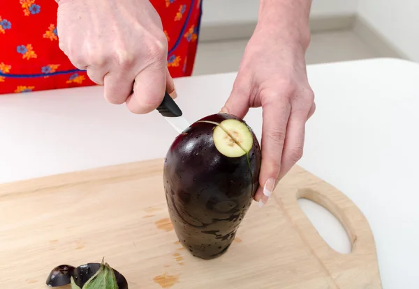 Handen van vrouw snijden aubergine — Stockfoto