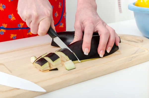 Händerna på kvinna skär aubergine — Stockfoto