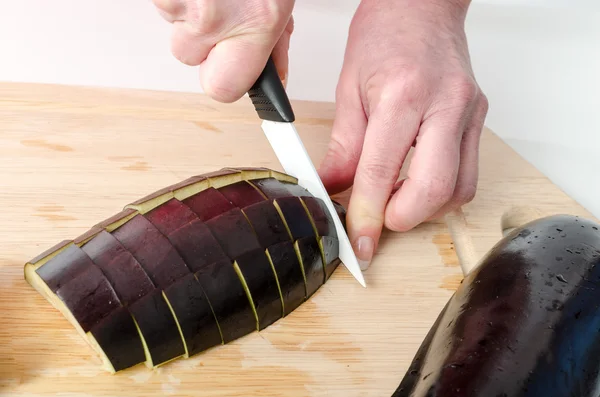 Händerna på kvinna skär aubergine — Stockfoto