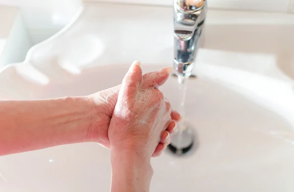 Mujer enjuagándose las manos — Foto de Stock