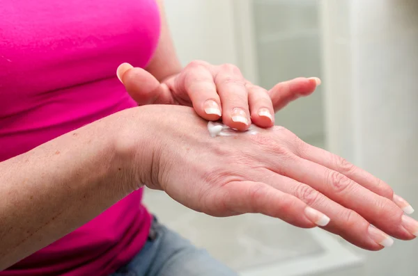 Mujer aplicando crema en su mano — Foto de Stock