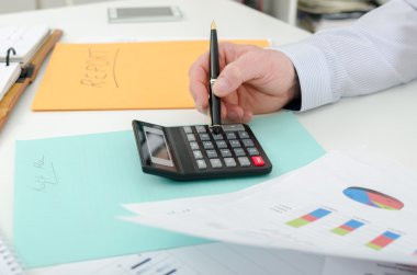Businessman typing on a calculator