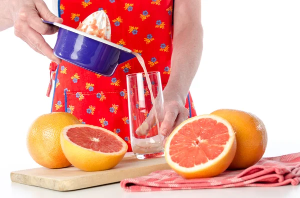 Женщина наливает свежий грейпфрутовый сок — стоковое фото