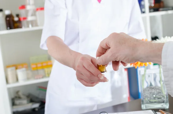 Doctor handing a bottle of pills to his assitant — Stock Photo, Image