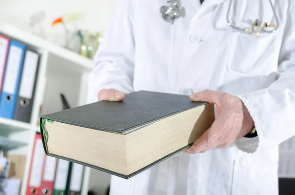 Medico in possesso di un libro medico — Foto Stock