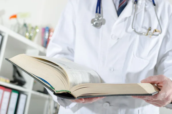Doctor doing research in a medical book — Stock Photo, Image