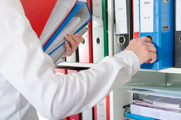 Zakenvrouw nemen bindmiddelen van een plank — Stockfoto