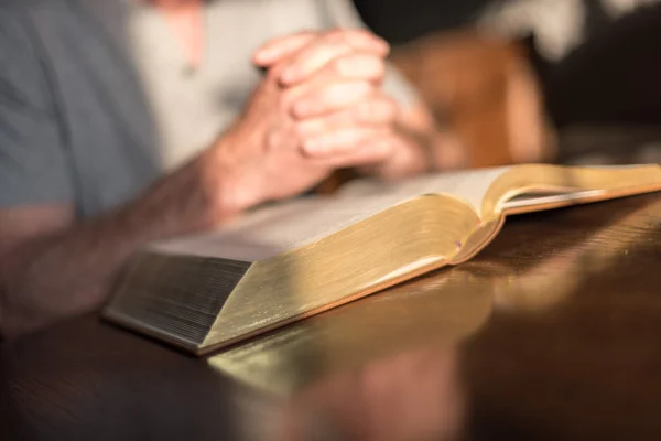 Homem orando mãos em uma Bíblia — Fotografia de Stock