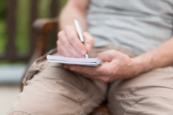 Uomo che prende appunti su un libro tascabile — Foto Stock