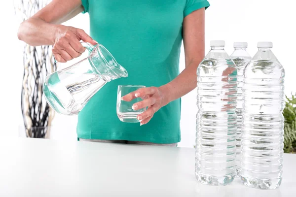 Kvinnan häller vatten i ett glas — Stockfoto
