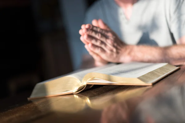 L'uomo che prega mani su una Bibbia — Foto Stock