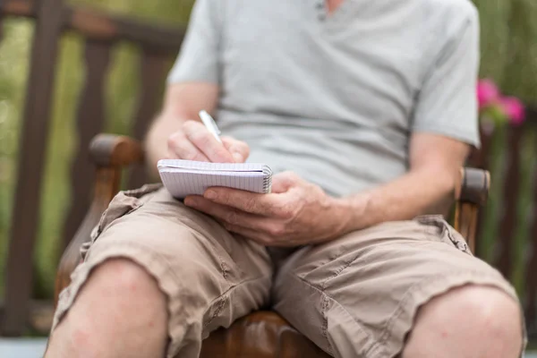 Uomo che prende appunti su un libro tascabile — Foto Stock